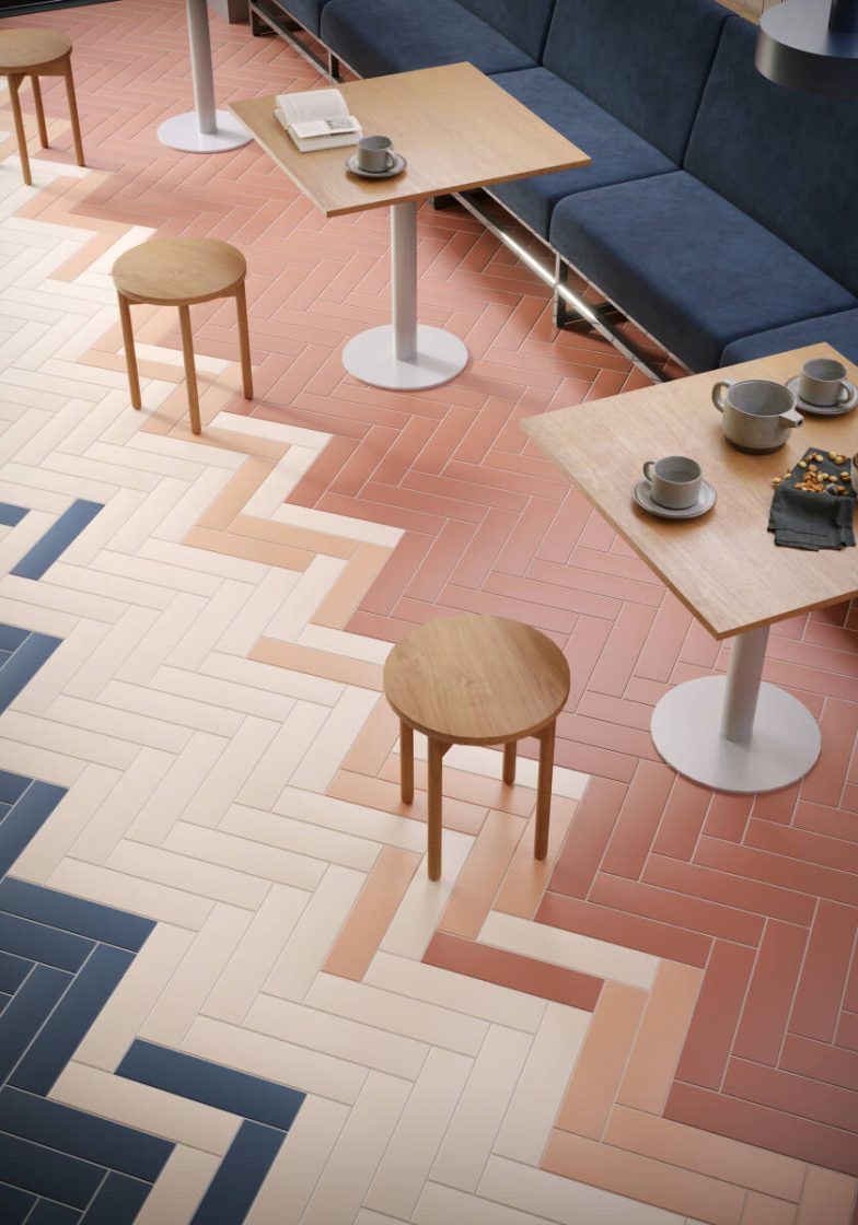 Visão de cima de piso de restaurante com revestimentos retangulares rosa, terracota e azul em zigue-zague