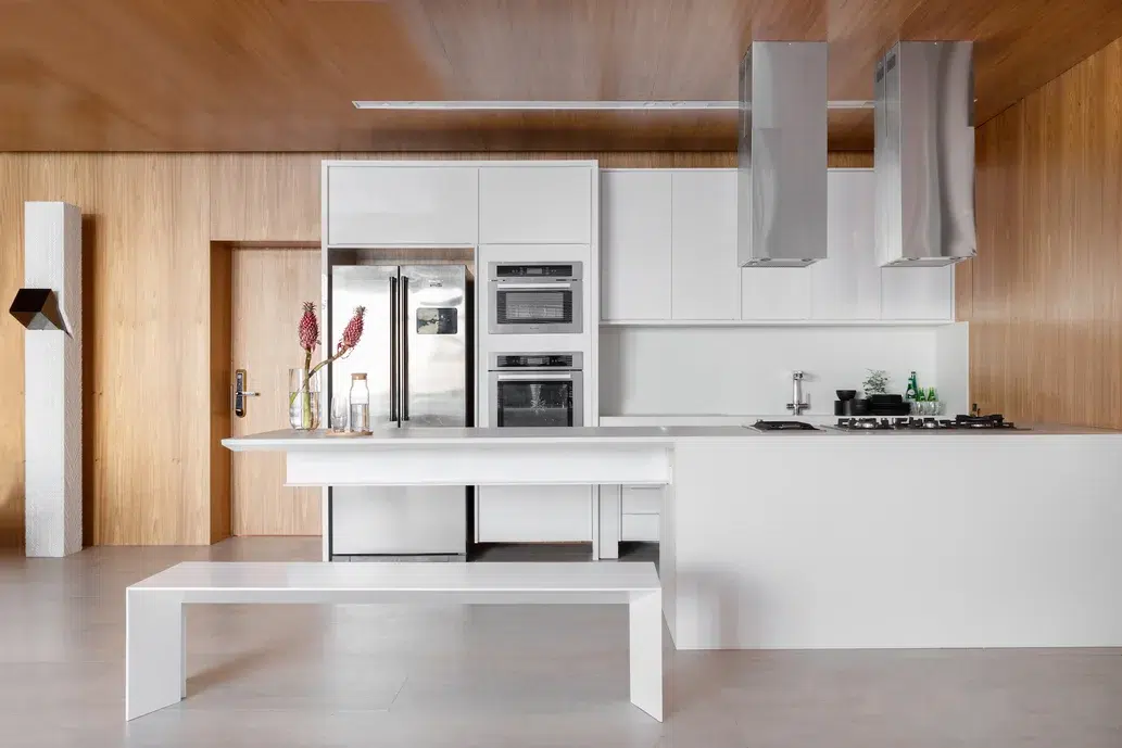Cozinha com móveis brancos e detalhes na cor prata.