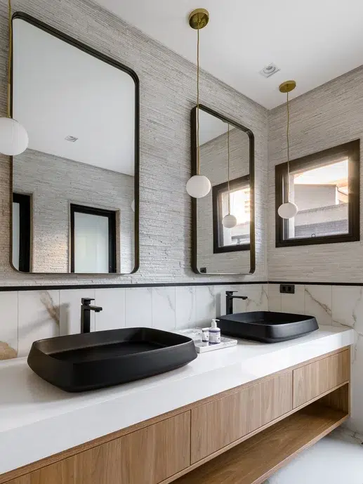 Banheiro com revestimento em mármore, duas cubas e dois espelhos.