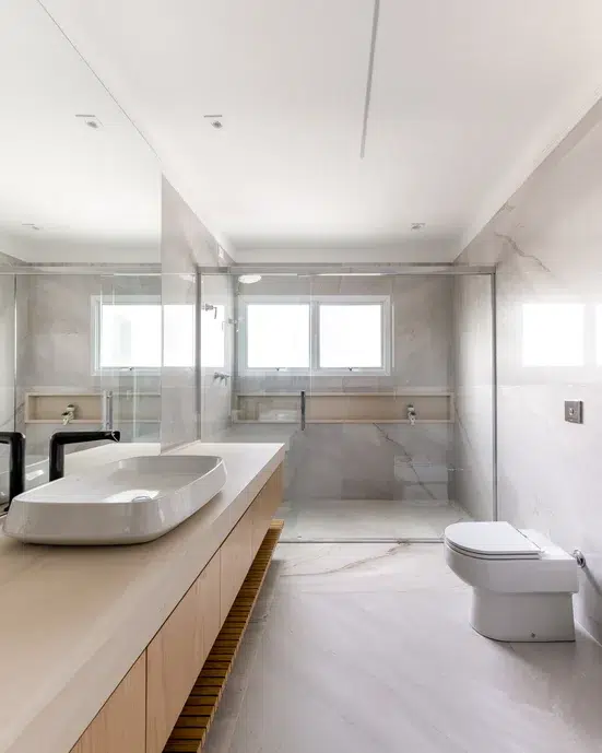 Banheiro com paredes e piso revestidos com porcelanato palissandro.  Marcenaria emmadeira Carvalho.