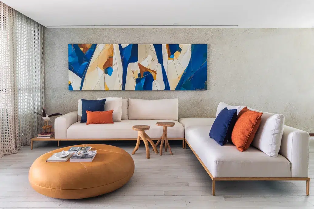 Sala com dois sofás juntos off-white, com decoração em tons terrosos e azul. 