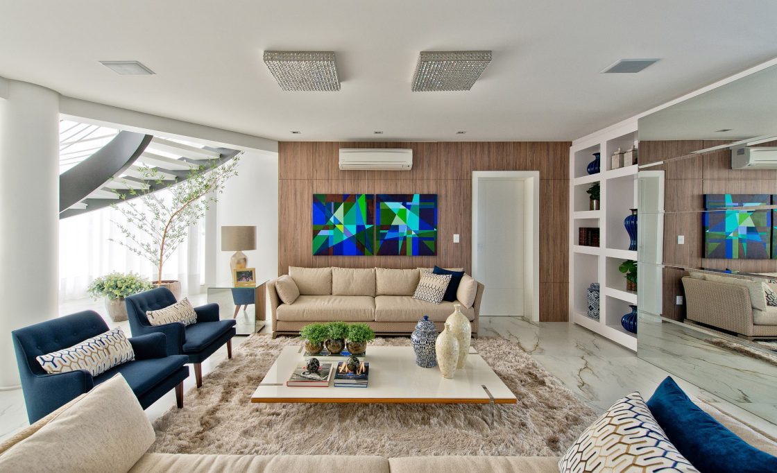 Sala de estar aconchegante com sofá de cor clara e poltronas coloridas 