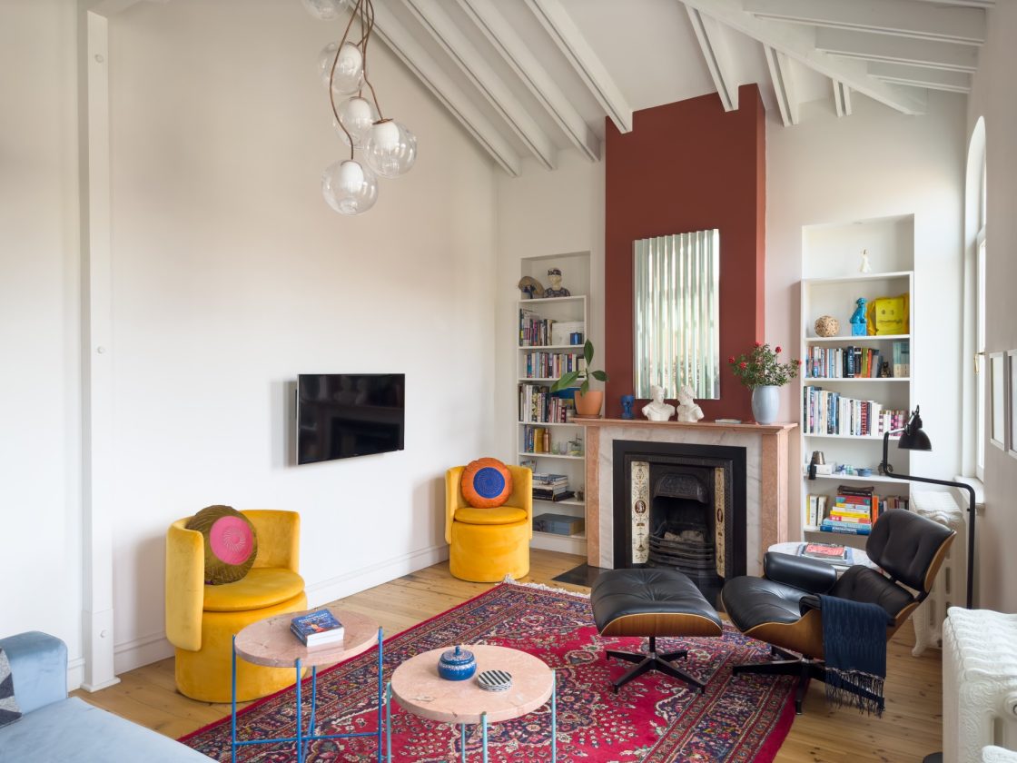 vista da sala de estar com tapete vermelho, poltronas amarelas e Eames Lounge chair 