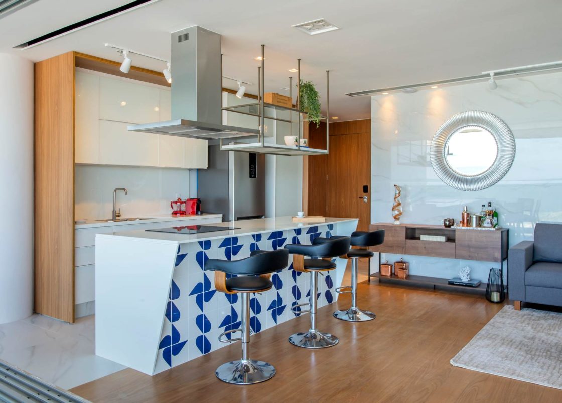 Cozinha integrada de apartamento de praia, com base neutra e detalhes azuis