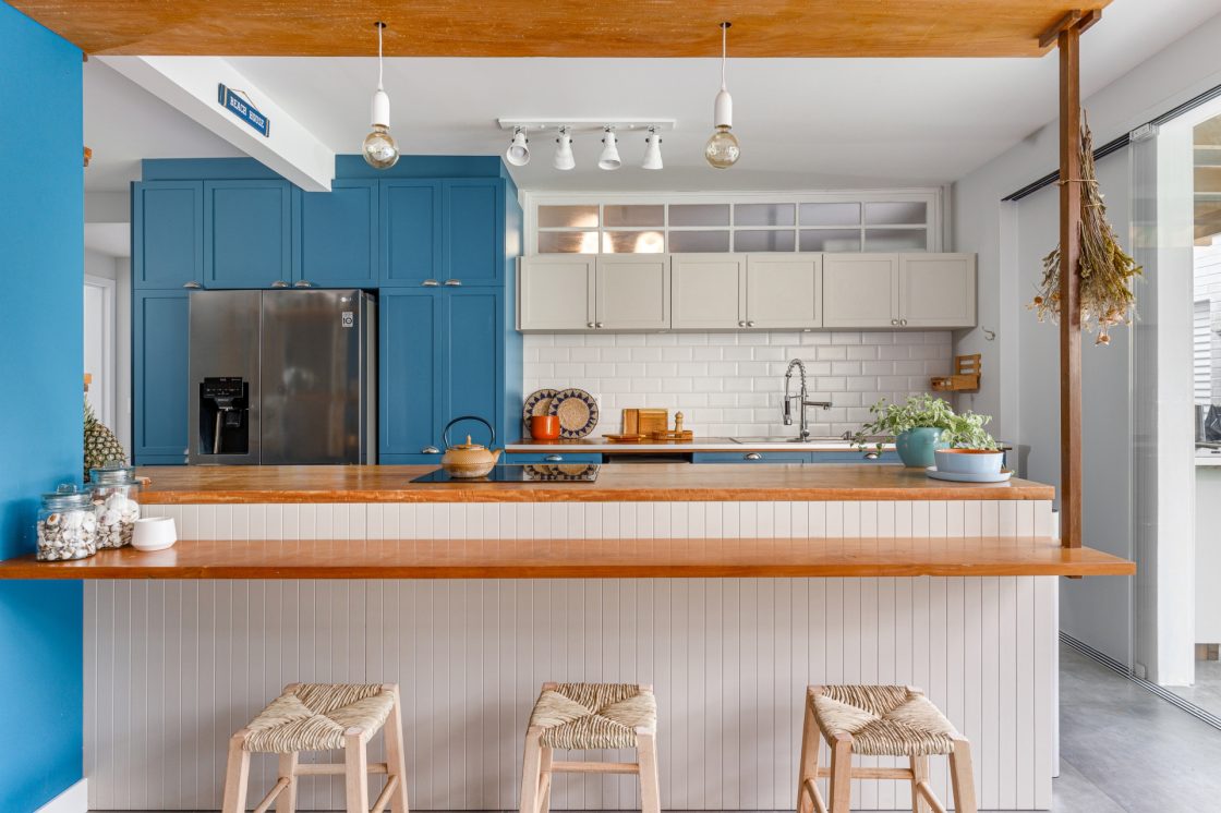 cozinha de casa de praia com banquetas de madeira e palha