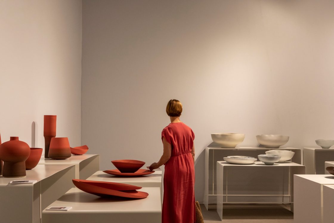 Mulher de vestido vermelho entre cerâmicas coloridas no salão do móvel de milão 