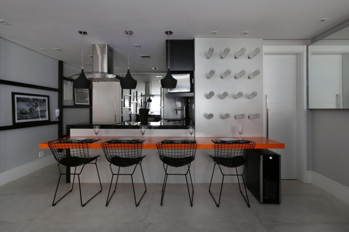 Cozinha com área de jantar em tons de preto, branco e cinza. Com mesa em destaque em tom alaranjado. 