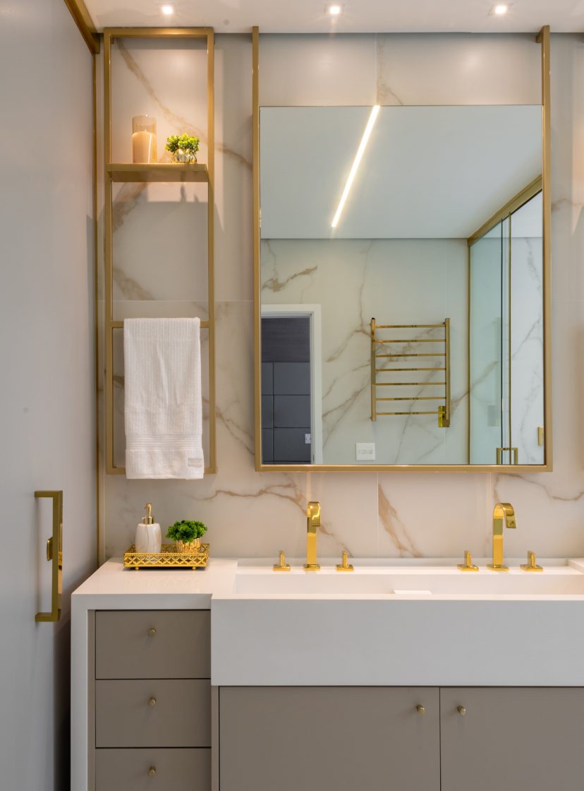 Banheiro com revestimento marmorizado e metais em dourado