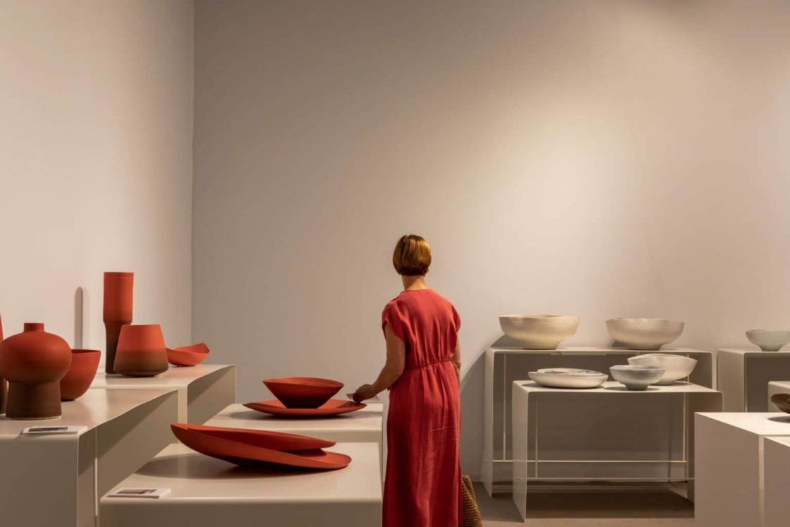 Mulher com roupa vermelha entre cerâmicas de mesma cor