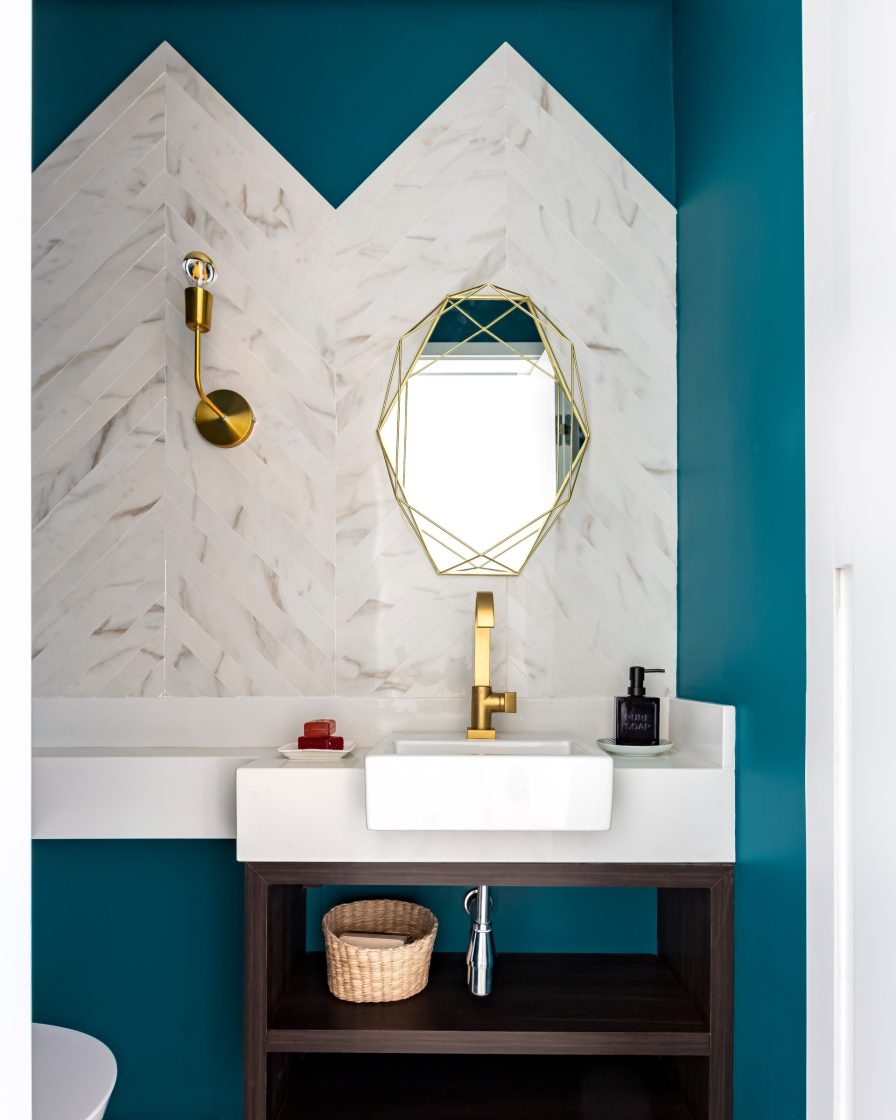 banheiro azul com bancada e cuba branca e espelho com moldura dourada 