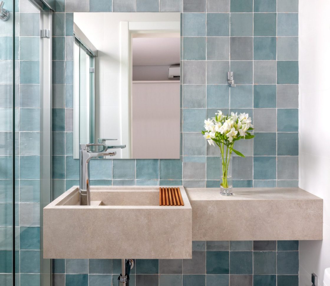 banheiro com revestimento azul em diferentes tons e pia de concreto