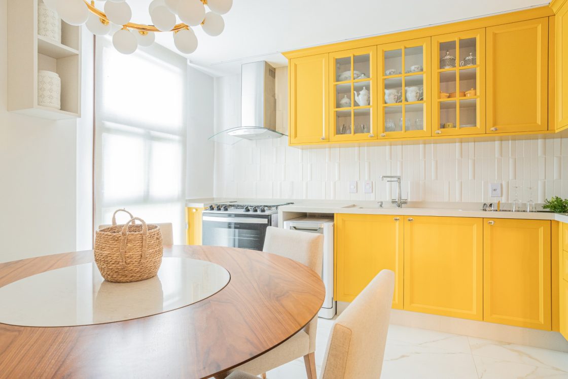 cozinha branca e amarela com cesto de palha sobre mesa de jantar 