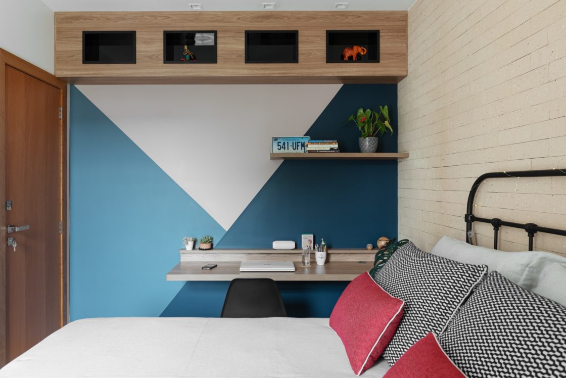 Quarto home office com desenhos gráficos na parede, na cor azul, na área de trabalho 
