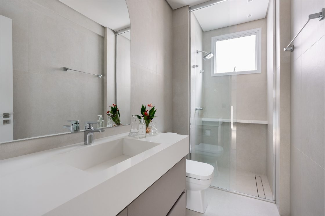 Banheiro branco iluminado com espelho grande.