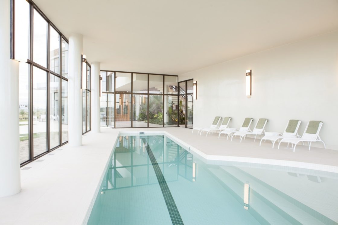 piscina coberta contemporânea, ambiente branco com fechamento em vidro,