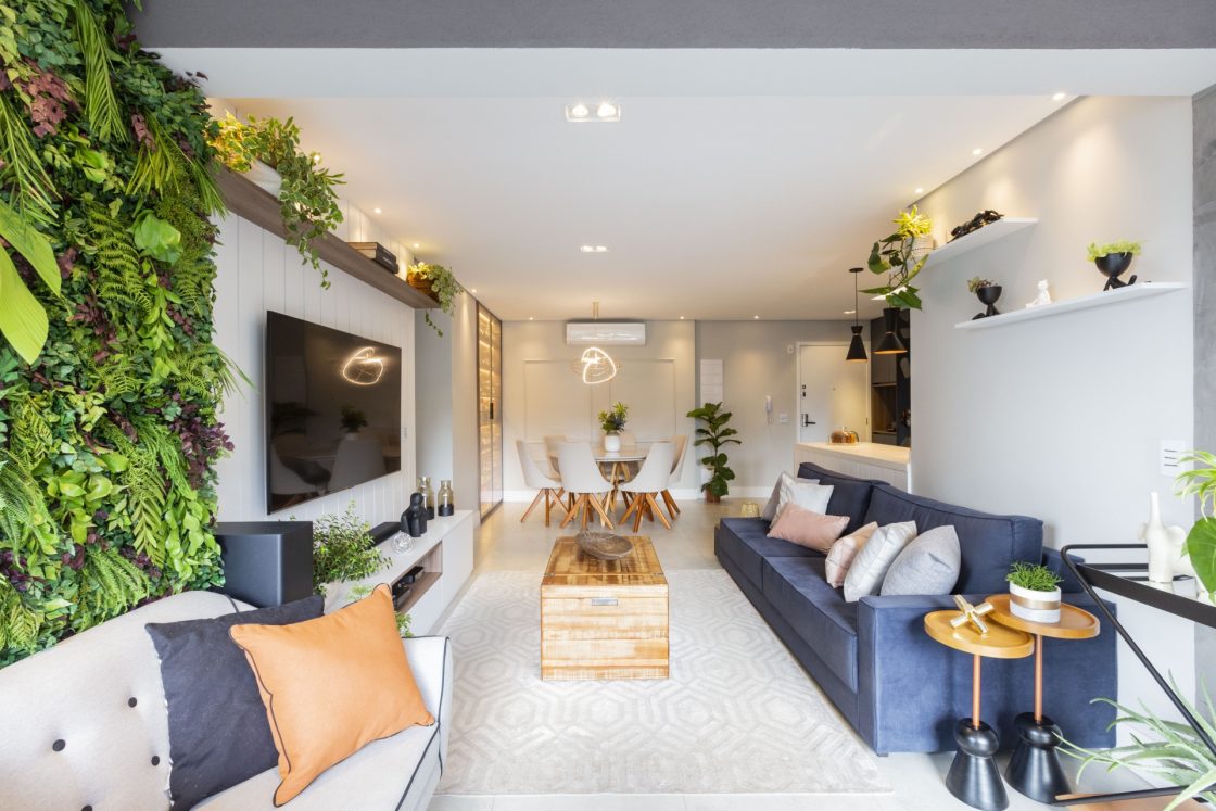 Sala de estar iluminada com jardim vertical incorporando o painel da televisão