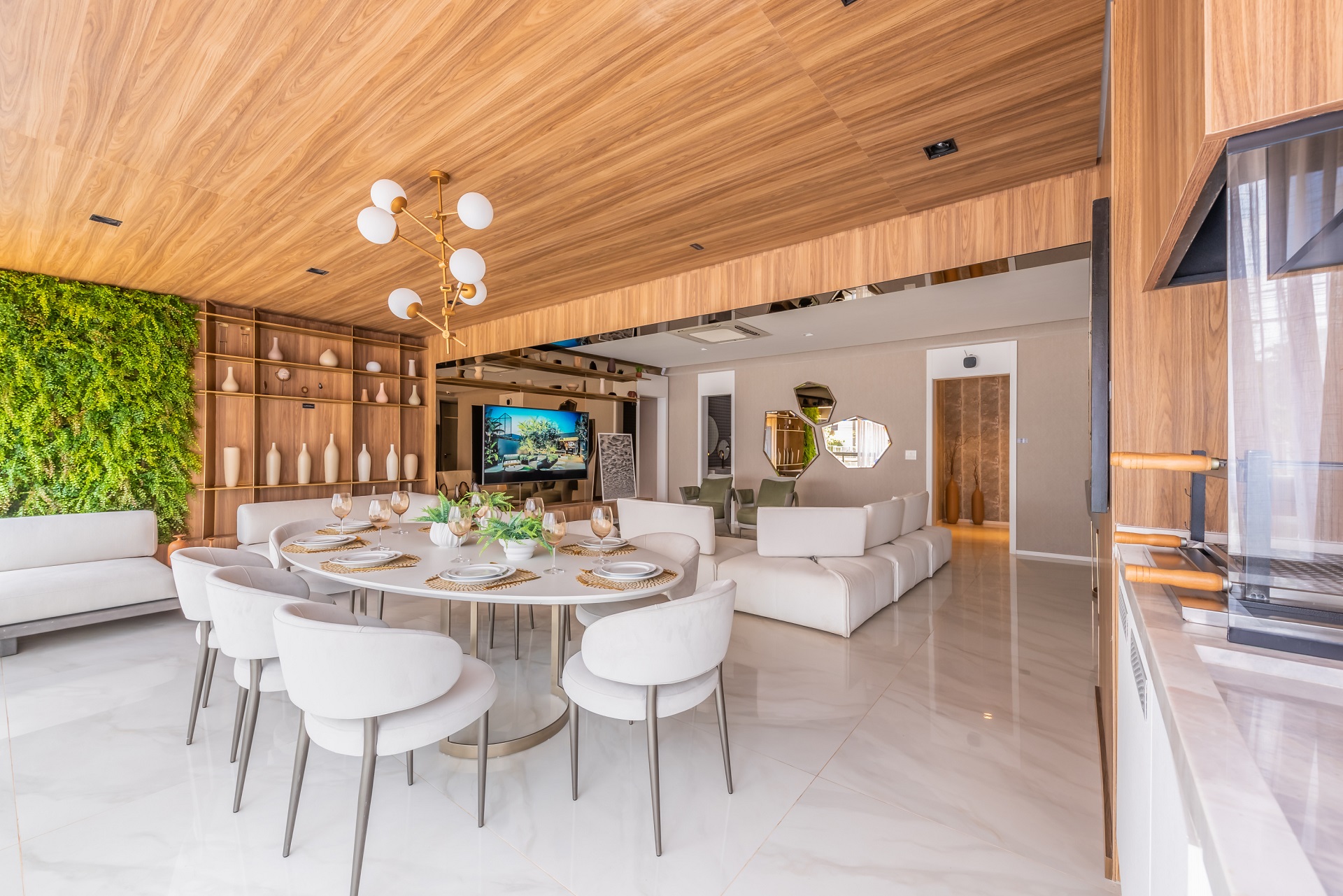 Sala integrada com piso de mármore, móveis claros, jardim vertical e teto de madeira