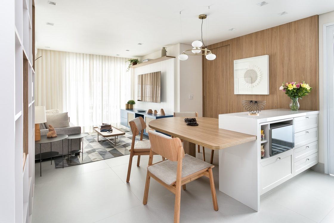 Sala e cozinha integradas em tons de madeira e branco