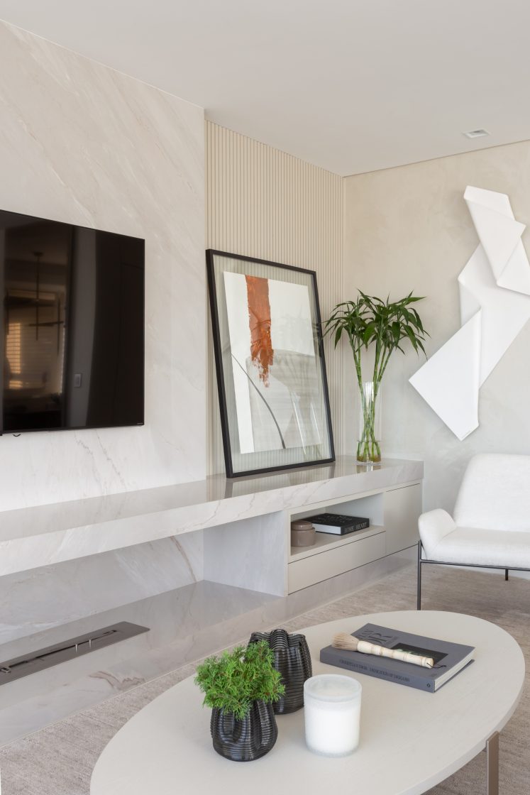 Sala de estar com bancada marmorizada e tv pendurada. Lareira ecológica 