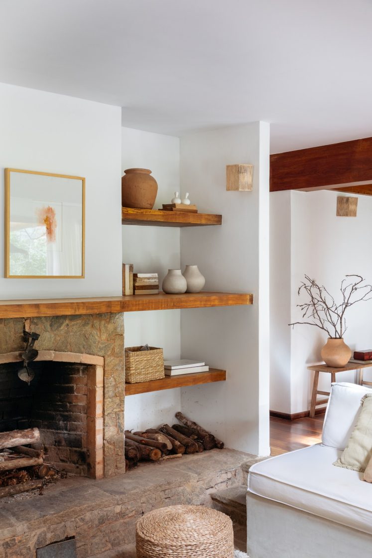 sala de estar com prateleiras de madeira, vasos de cerâmica, parede branca, piso de madeira e sofá branco 
