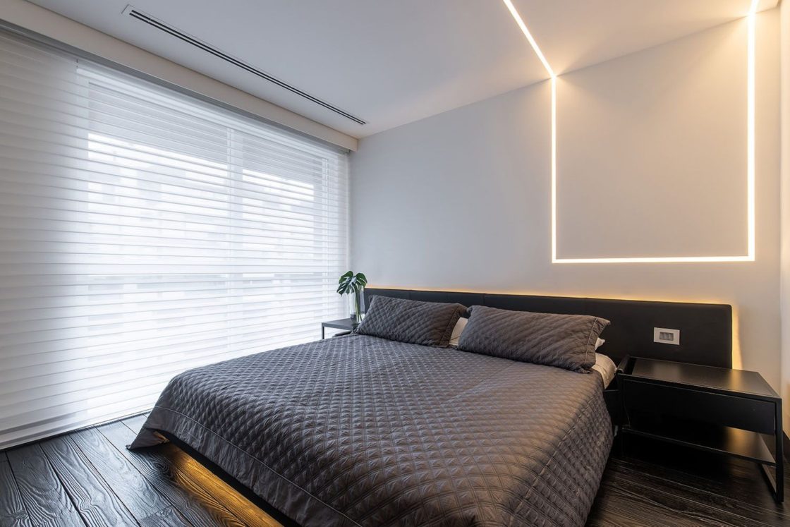 quarto minimalista com piso preto, parede branca e luz de led