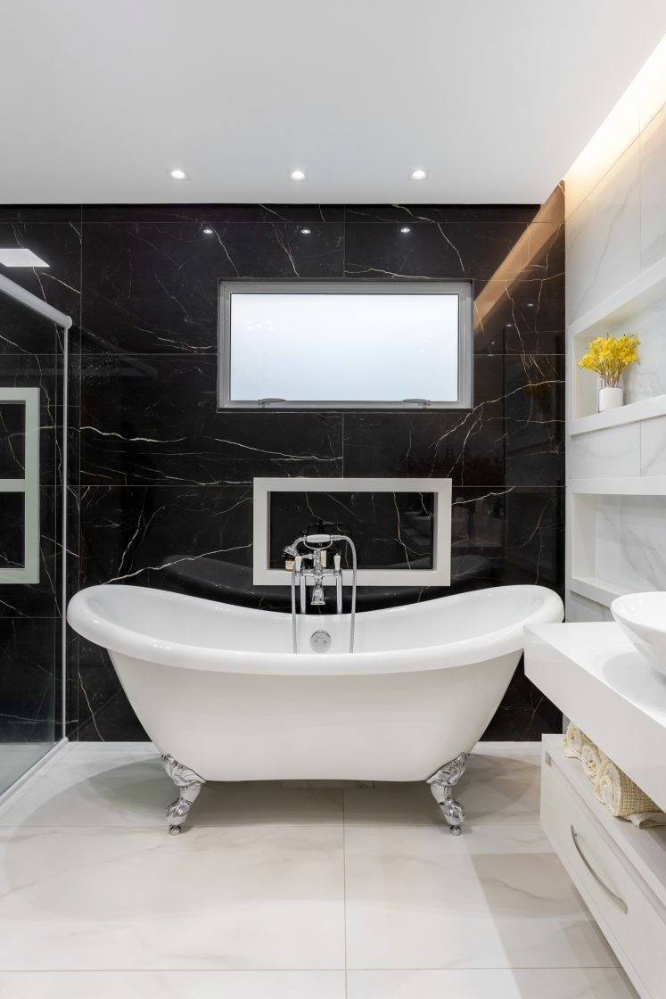 Banheiro com banheira vitoriana e paredes em mármore preto