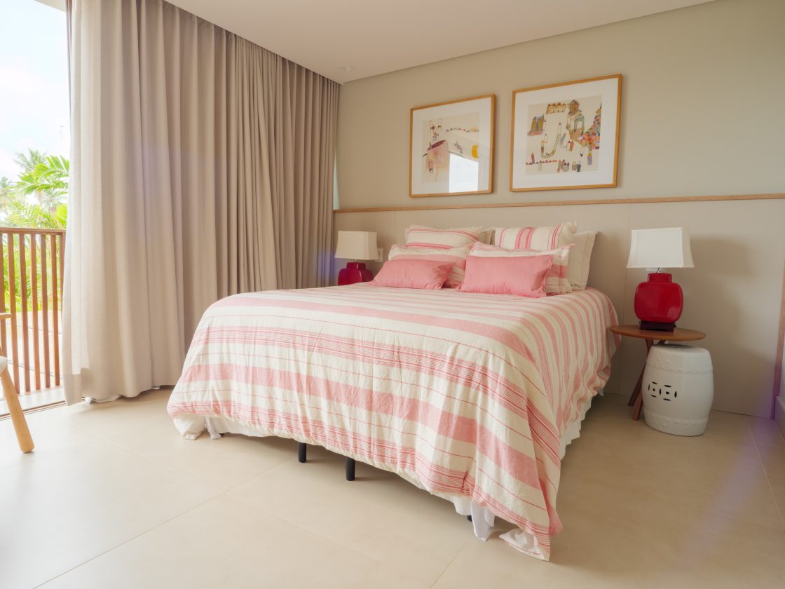 Quarto feminino na cor rosa e branco com luminárias com base vermelha nas cabeceiras