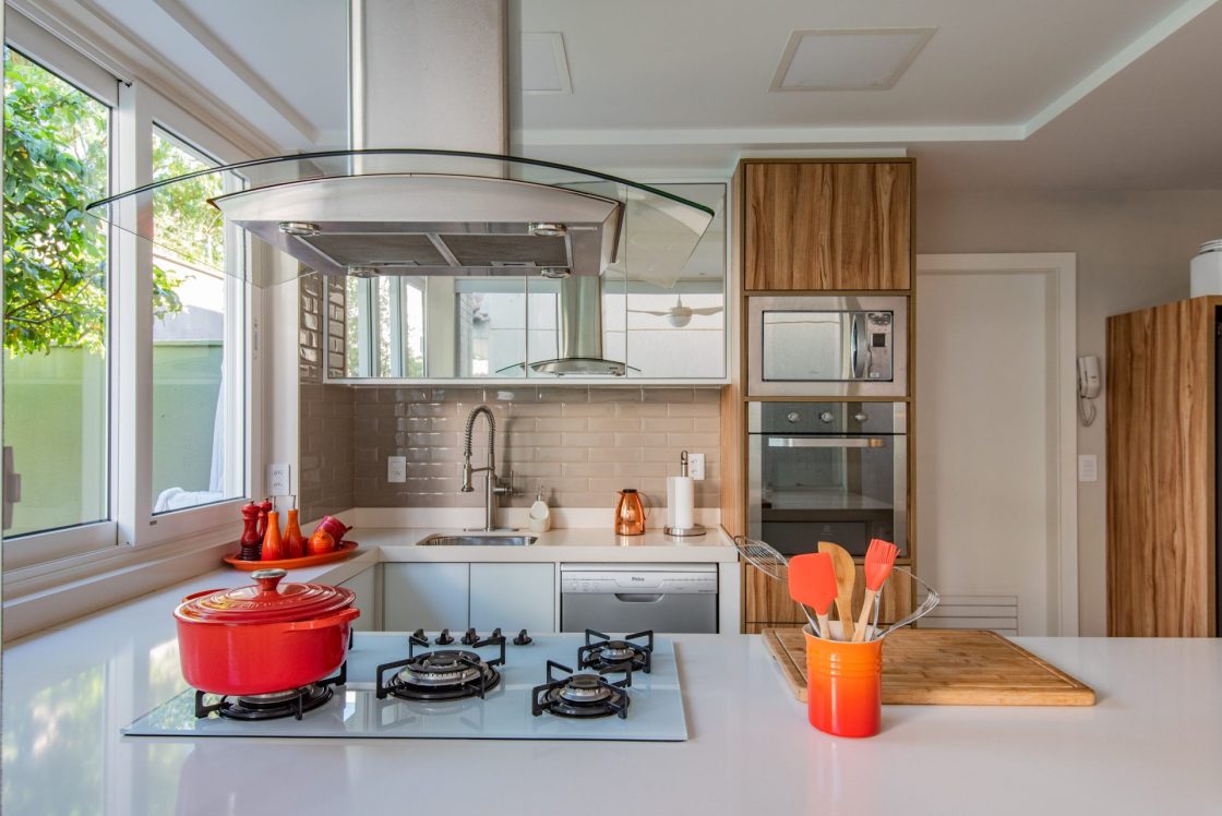 Cozinha com cores neutras e utensílios coloridos nas cores vermelho e laranja