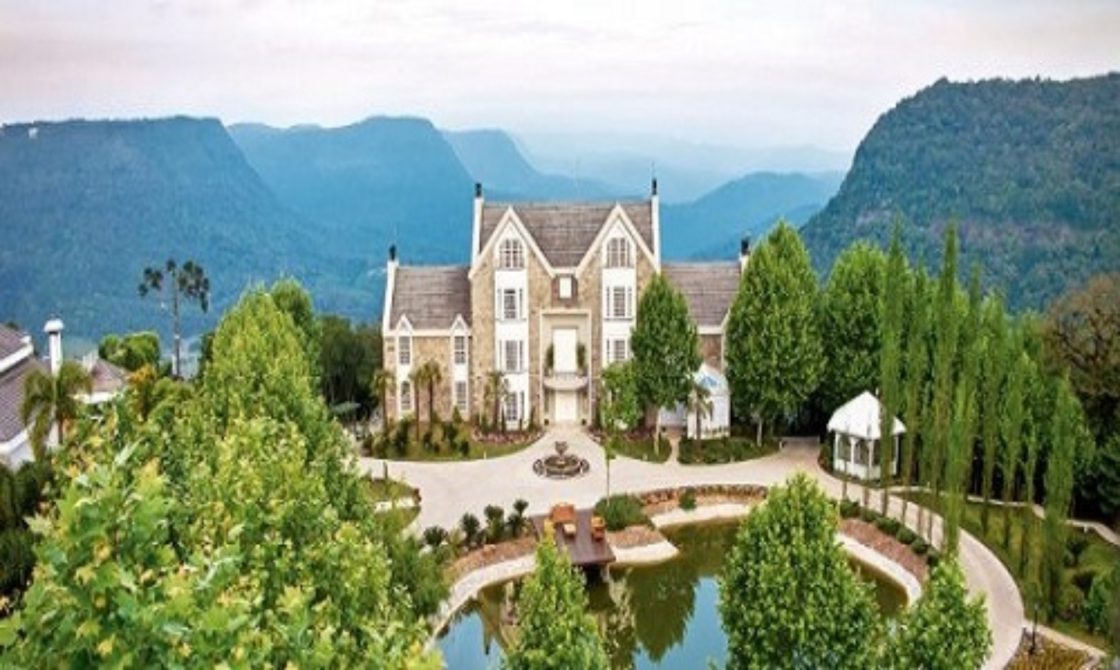 Castelo no alto de uma montanha com lago na entrada e cercado por vegetação local