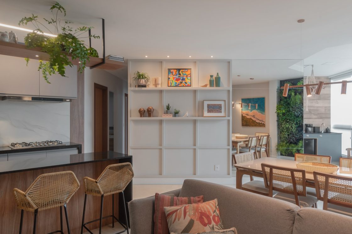 Sala de estar integrada com cozinha com ilha em madeira e pedra preta, criando um ambiente casual e aconchegante 