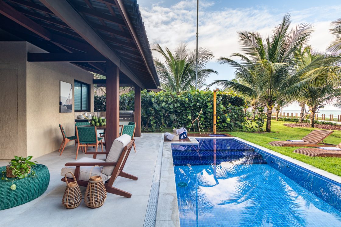 Quintal de casa de frente para a praia com piscina de dois níveis e espreguiçadeira em madeira