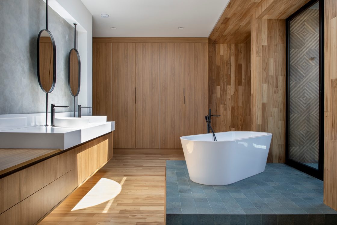 Amplo banheiro com detalhes em madeira, gabinete duplo e banheira em destaque