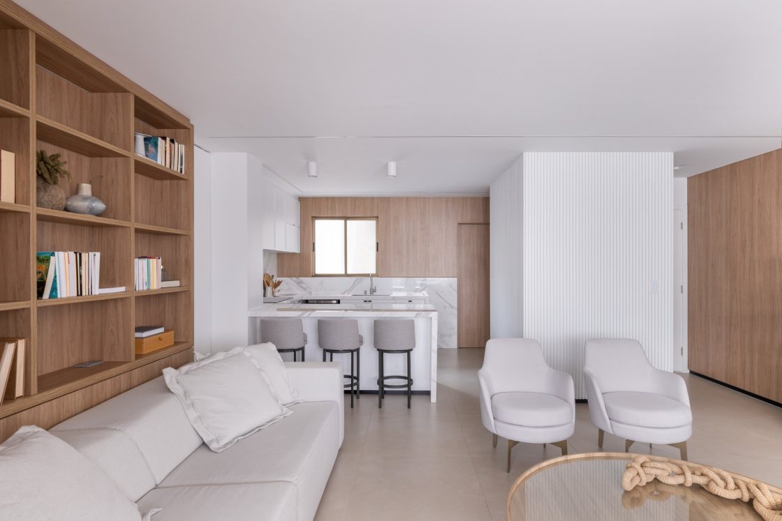 cozinha pequena com mármore branco, sala com mobiliário de madeira e estofados brancos