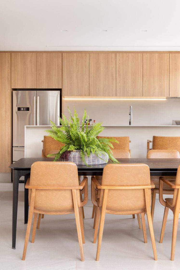 Cozinha gourmet com design escandinavo, cadeiras e armários em tons claros de madeira, e revestimentos claros