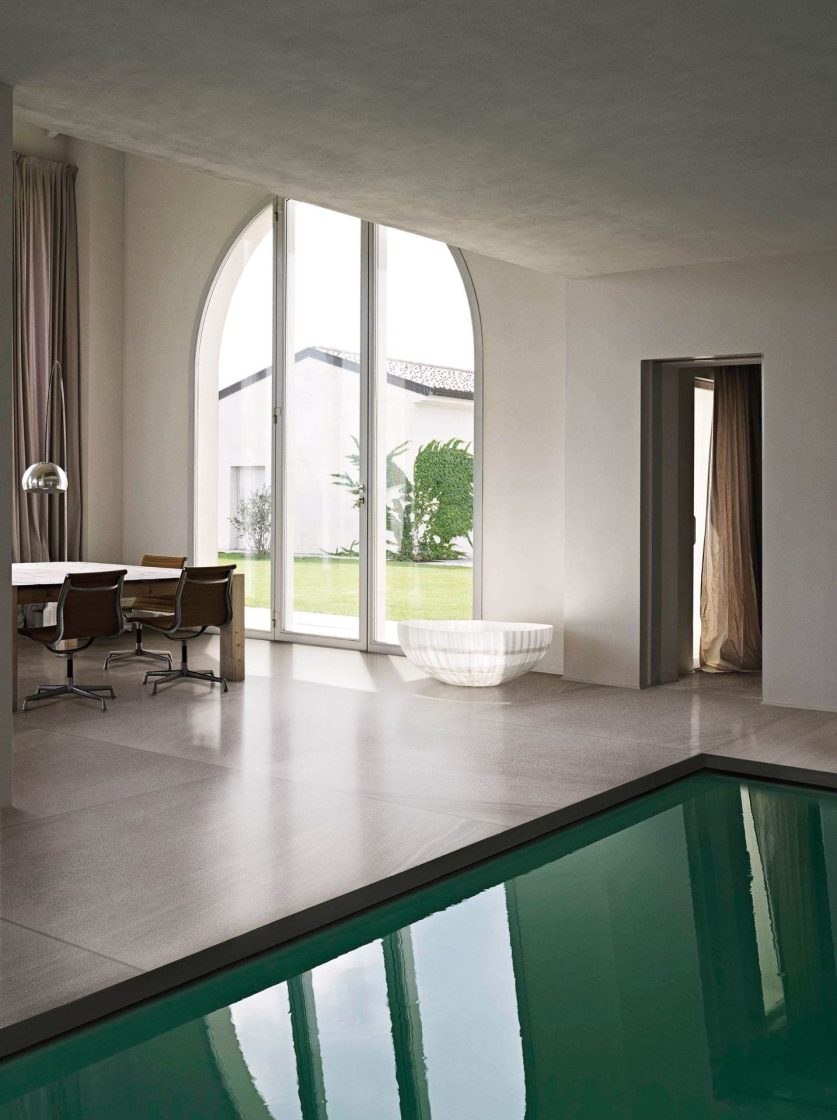 Ambiente minimalista com porta de vidro em formato de arco e piscina