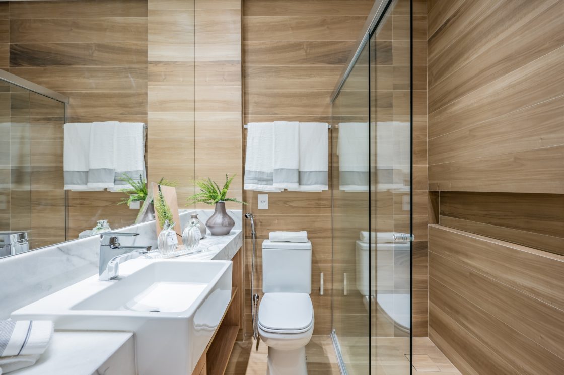 Banheiro com paredes em madeira e detalhes em porcelanato branco