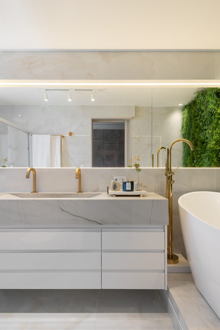 Gabinete de banheiro com cuba em pedra clara e elementos em destaque em dourado