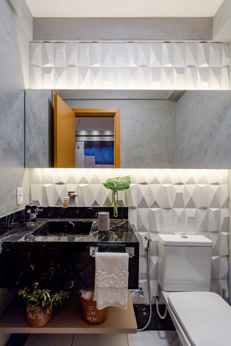 Banheiro com pia em mármore escuro e paredes em relevo 