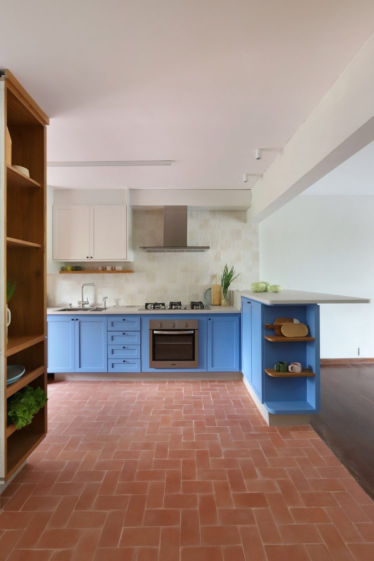 Cozinha ampla com piso terracota, paredes claras e marcenaria azul