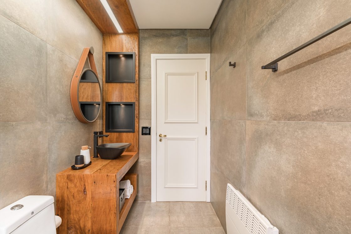 Banheiro revestido com aço corten, bancada de madeira e detalhes em couro