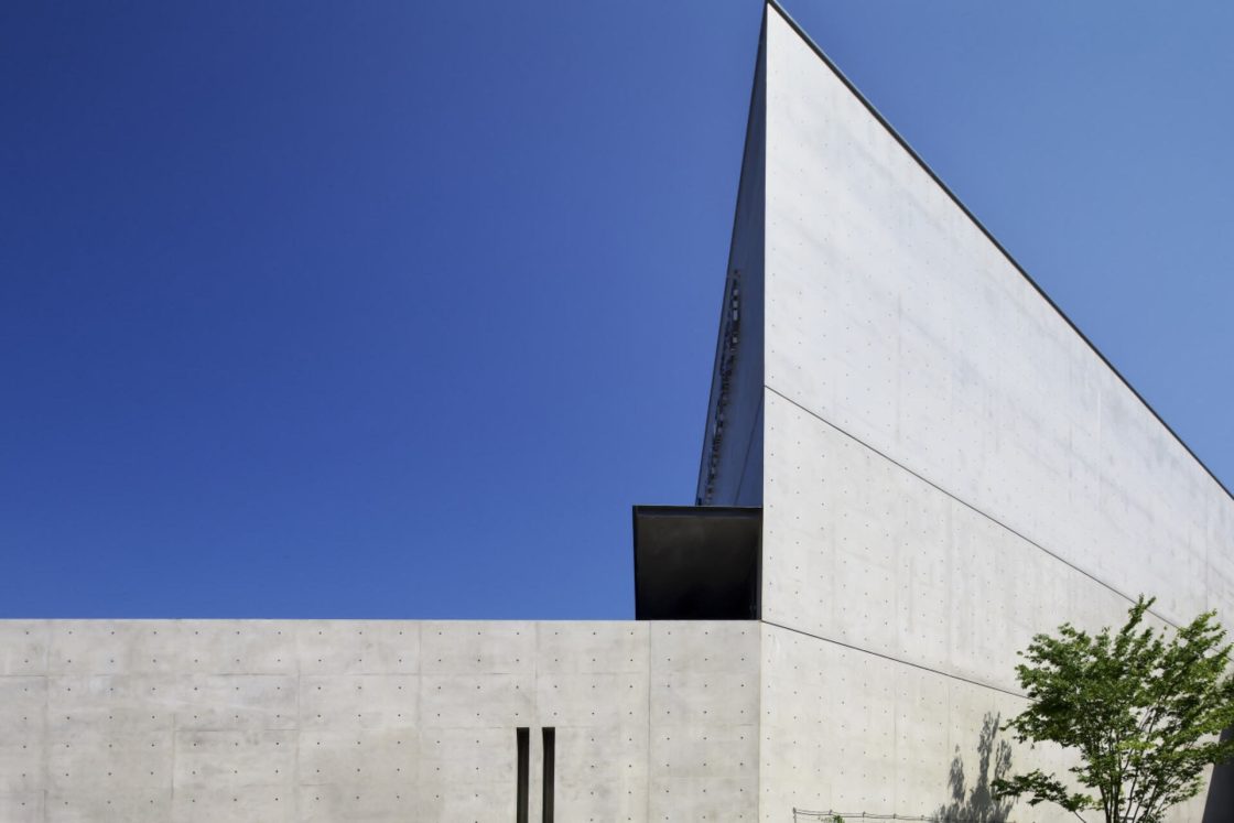 Akita museu, edifício em concreto aparente com formas retas fotografado em dia ensolarado com céu azul.