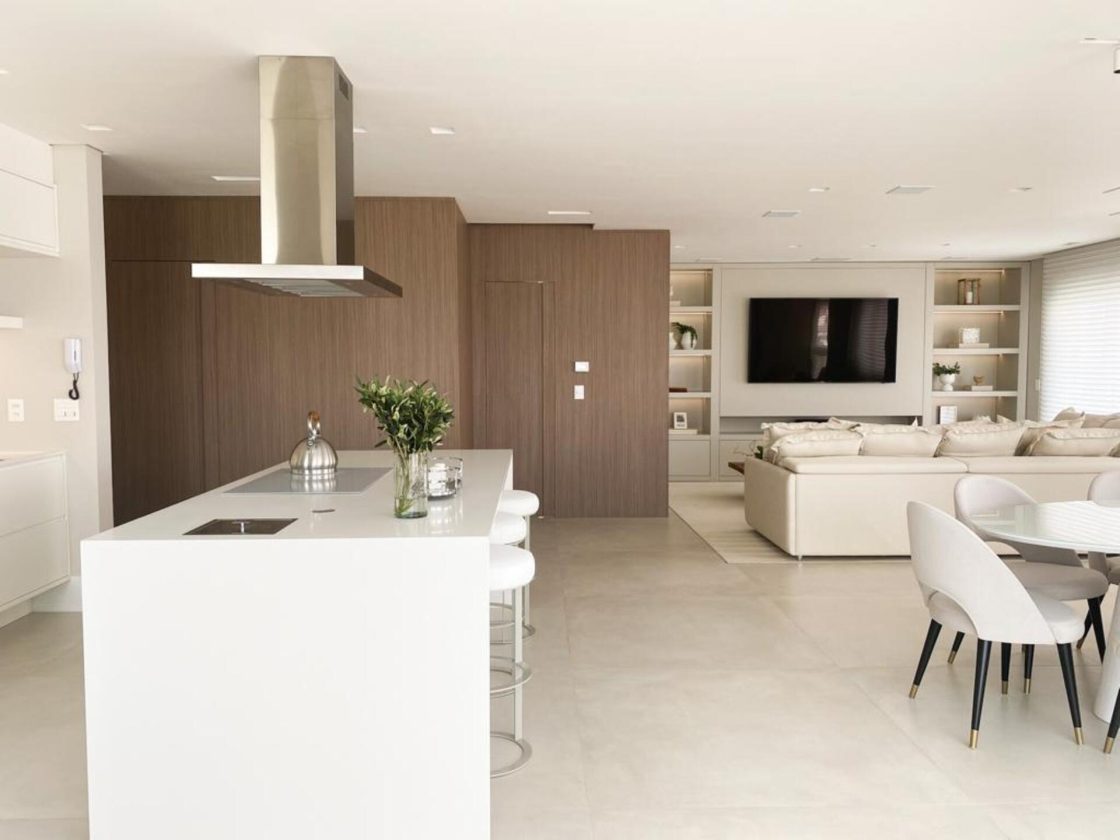 Vista da cozinha integrada com sala e sala de jantar em um apartamento duplex, tons claros e decoração minimalista