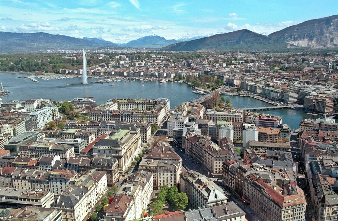 Vista aérea da cidade de Genebra, com diferentes edificações à frente de um rio