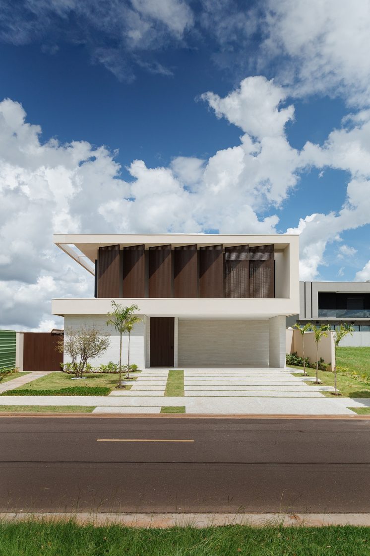 Casa branca com visual contemporâneo; brises marrons no fechamento do segundo pavimento