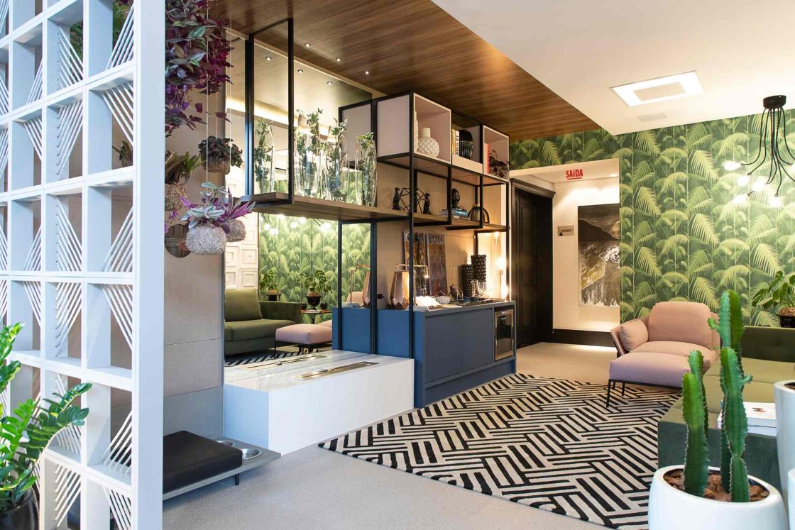 Sala de estar rica em detalhes: cobogós, plantas, marcenaria azul, tapete estampado, teto de madeira e papel de parede verde
