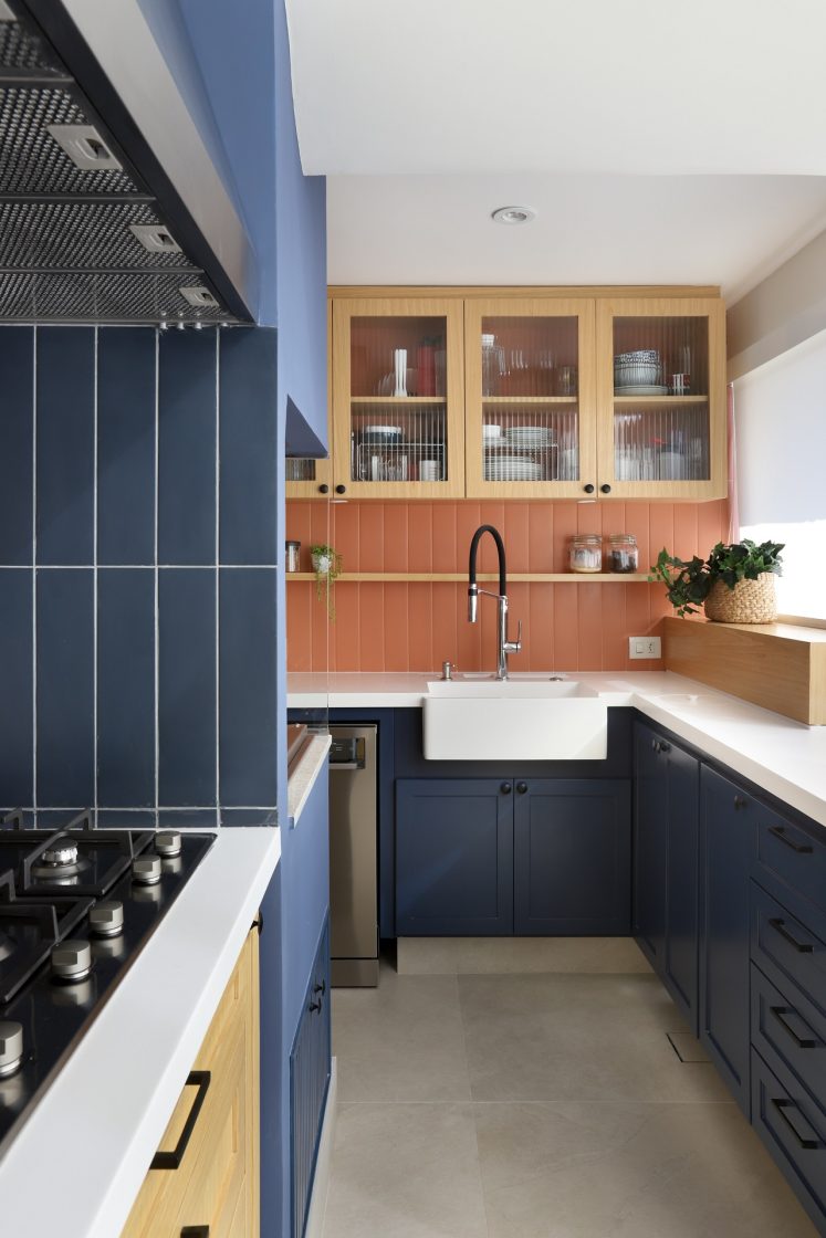 Cozinha em tons terrosos, com paredes revestidas de azul e laranja, além de marcenaria em azul e madeira