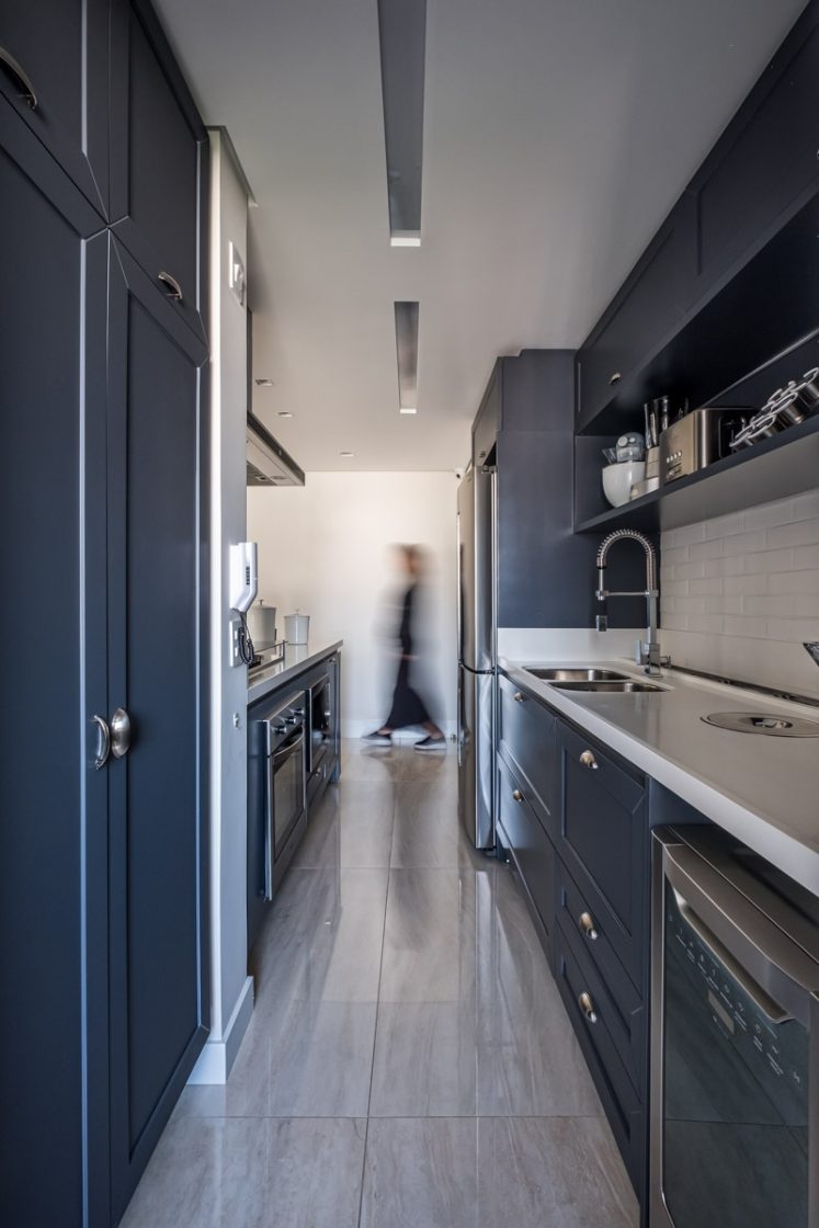 Cozinha com armários azul-marinho, eletromésticos embutidos e pia de bancada clara