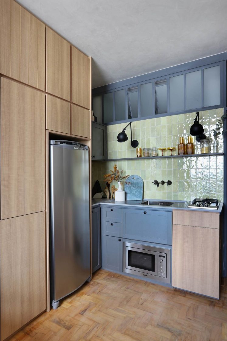 Cozinha com armários e janelas azuis, revestimento verde-claro e armários em madeira