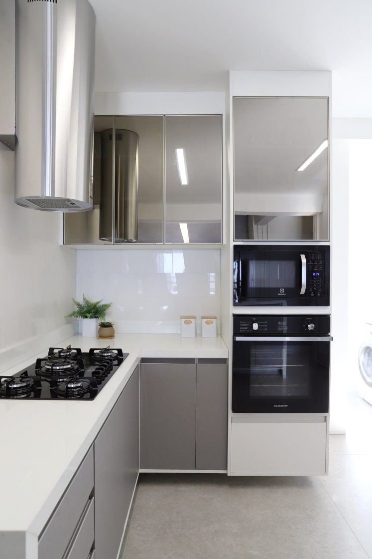 Cozinha moderna com bancada em "L", eletrodomésticos pretos e armários espelhados