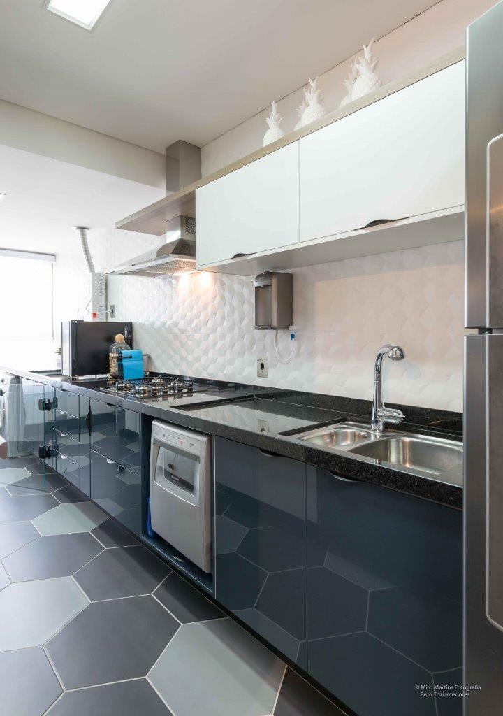 Cozinha com revestimentos em formato de hexágono, armários brancos e azul-marinho, pia e outros eletrodoméstico embutidos